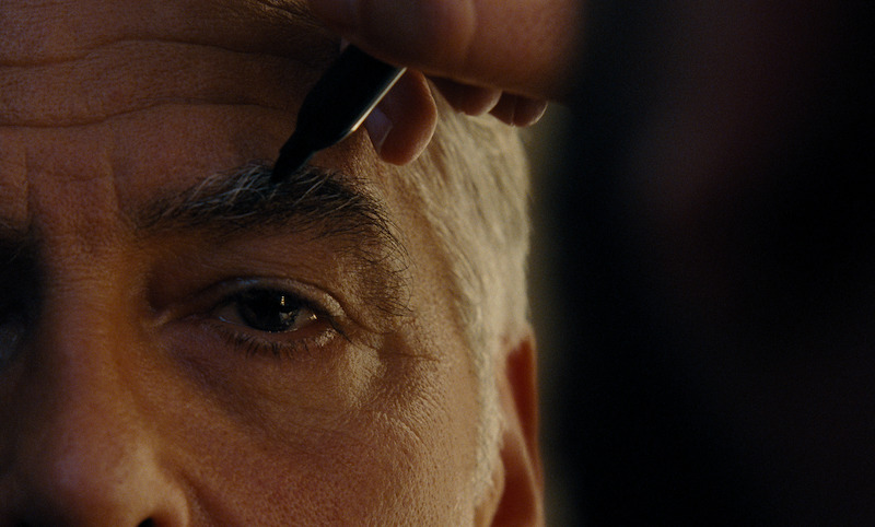 An extreme close-up of Jay Kelly (George Clooney) having his eyebrows darkened with a permanent marker.