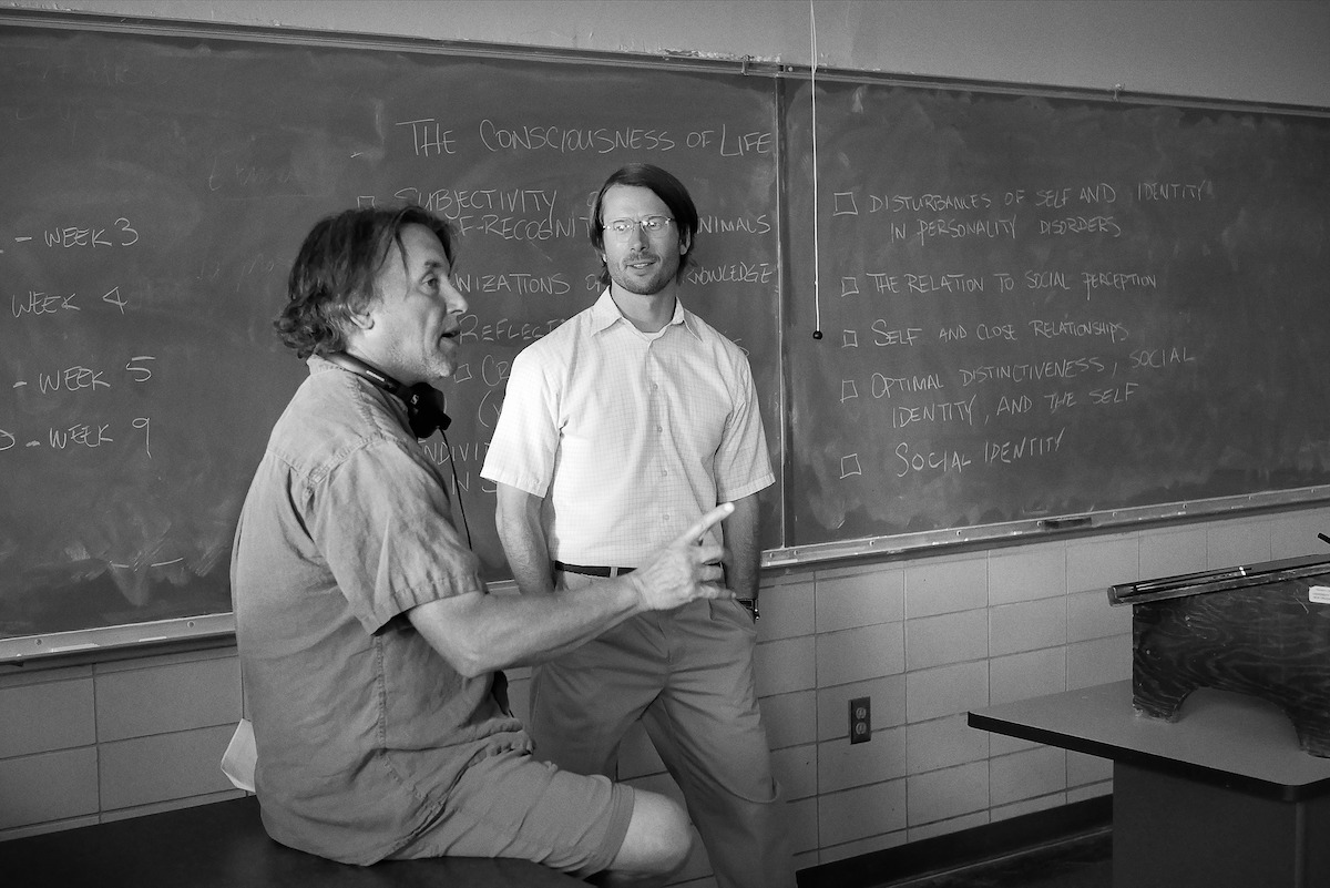 Richard Linklater and Glen Powell stand in a classroom.