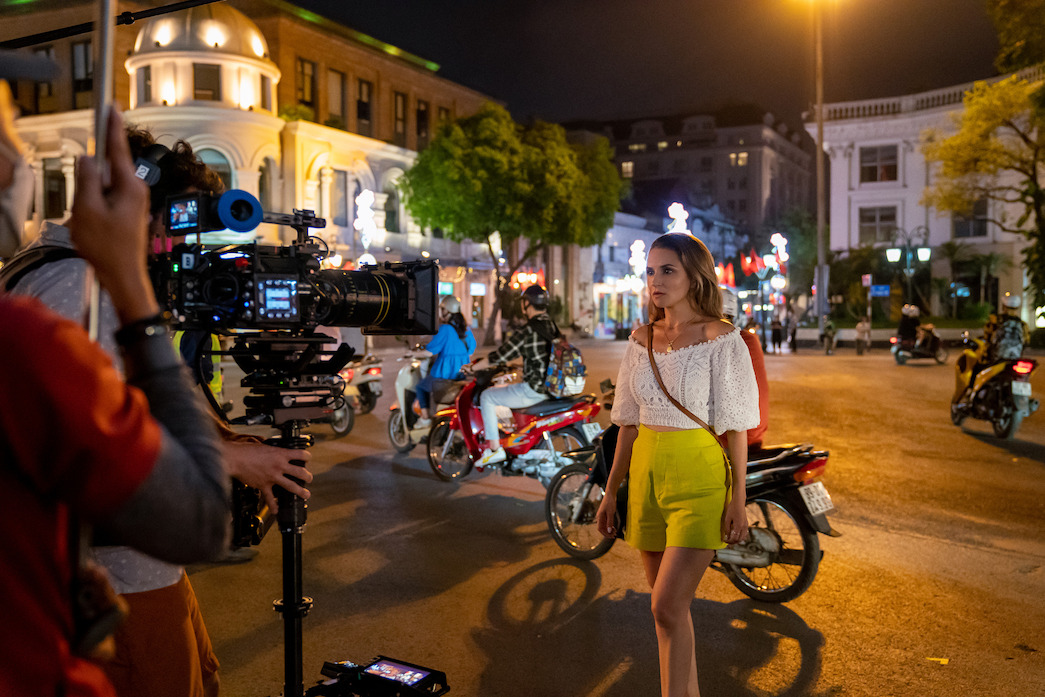 Rachael Leigh Cook films a nighttime scene on a Hanoi sidewalk.