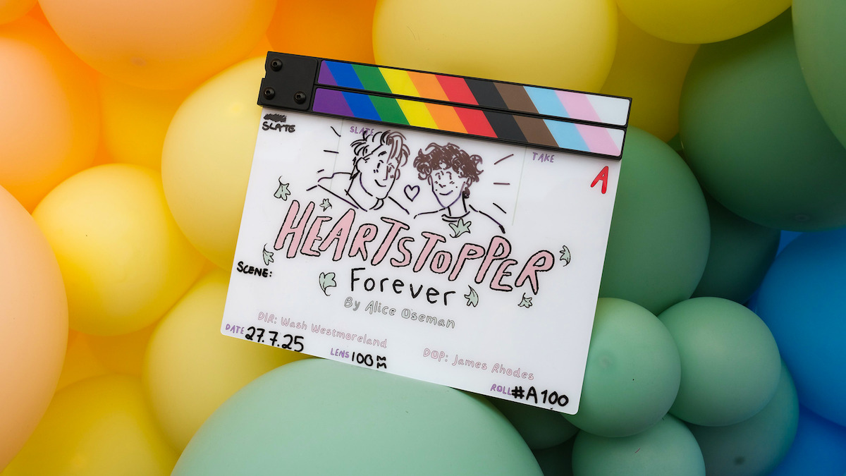 A film clapperboard with "Heartstopper Forever" illustrated, featuring two drawn characters and surrounded by colorful pastel balloons in the background.