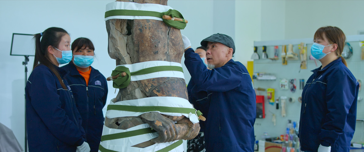 Excavators stand around a terracotta statue in the documentary film ‘Mysteries of the Terracotta Warriors.’