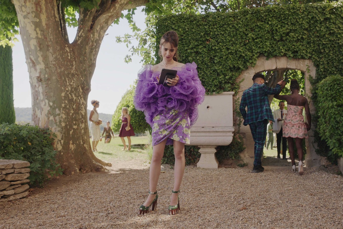 Lily Collins as Emily stands in a lavender dress in ‘Emily in Paris.’
