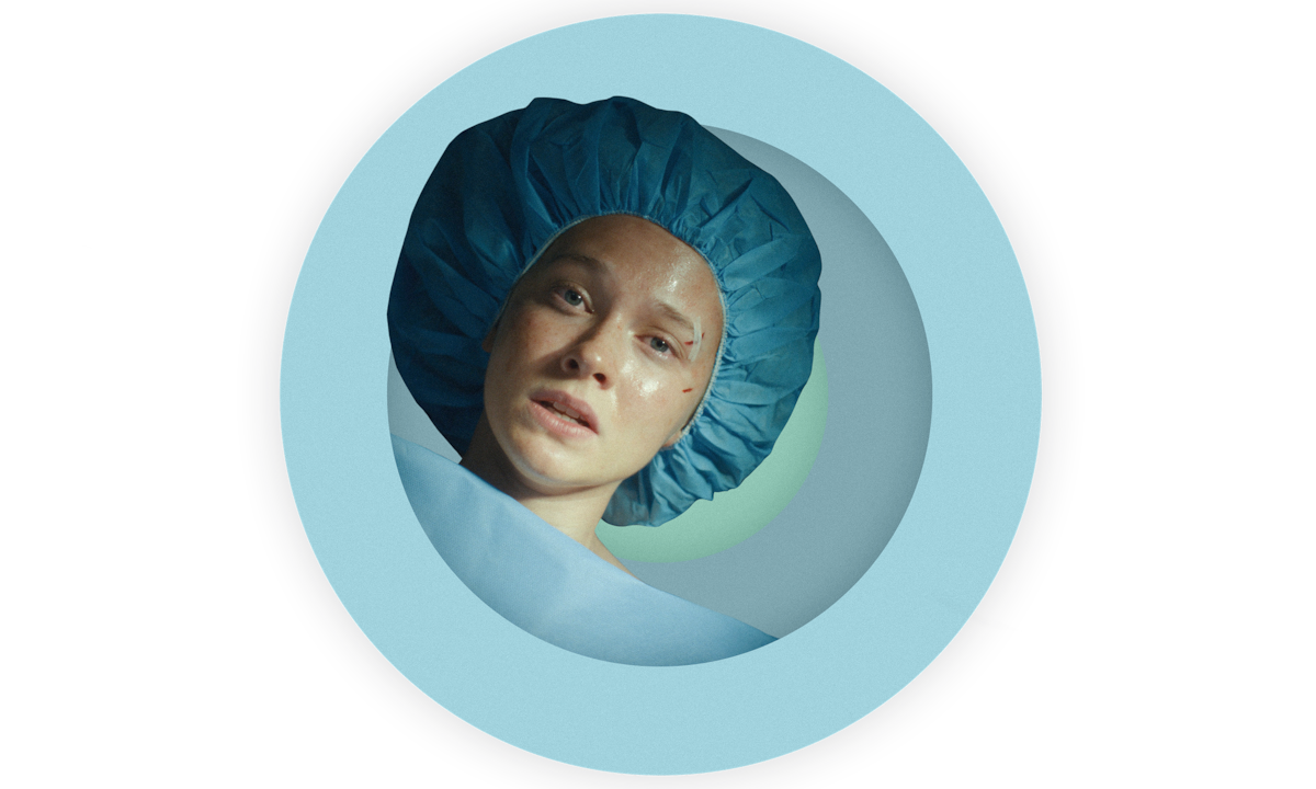 A spot photo illustration of Cailee Spaeny as Ashley wearing a blue hospital hairnet and covered with a blue sheet just before she goes into surgery in BEEF Season 2.