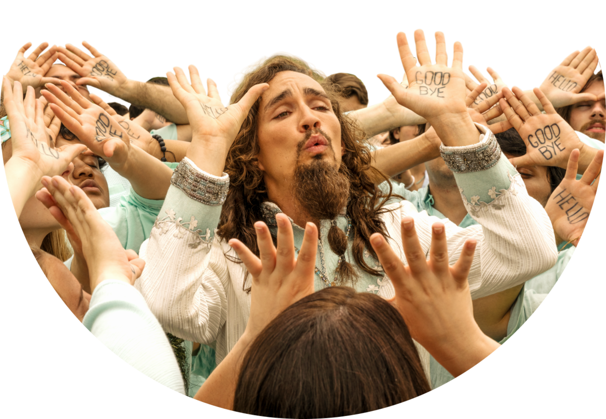 Robert Sheehan as Klaus stands in a crowd of people with their arms raised above their heads in Season 2 of ‘The Umbrella Academy’