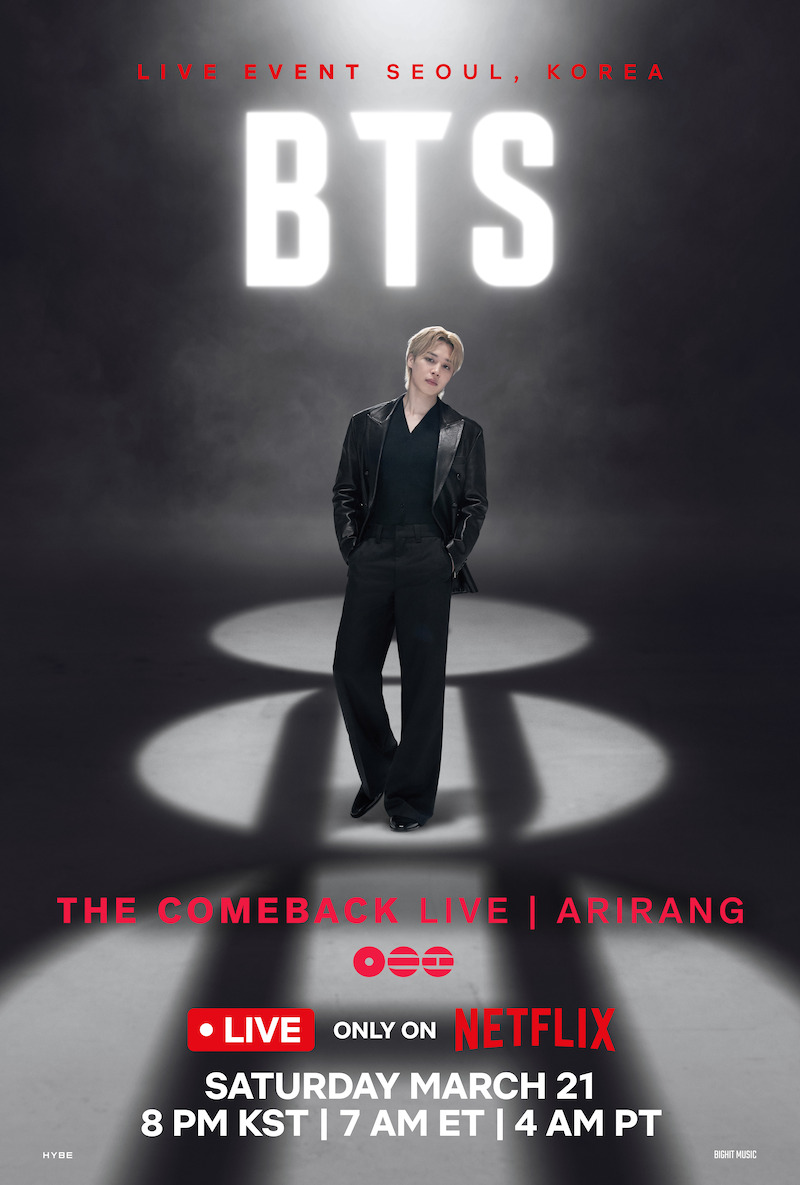 Jimin in a black suit stands confidently on stage under a spotlight, with large glowing "BTS" text and "Live Event Seoul, Korea" in red above, set against a dark, smoky background.