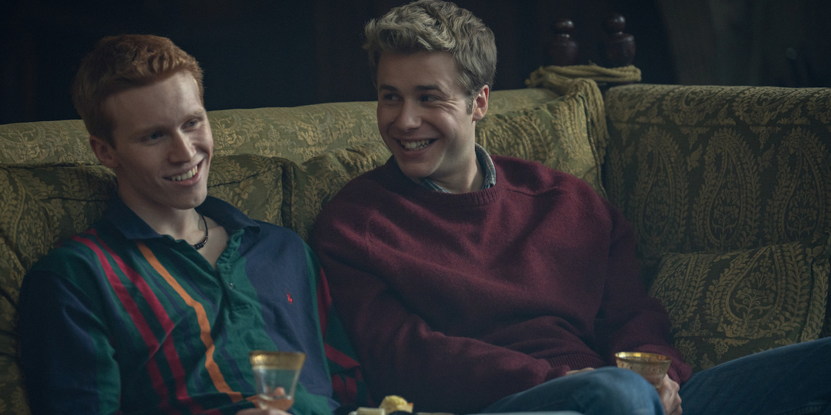 Prince Harry and Prince William sitting on a couch laughing in ‘The Crown.’