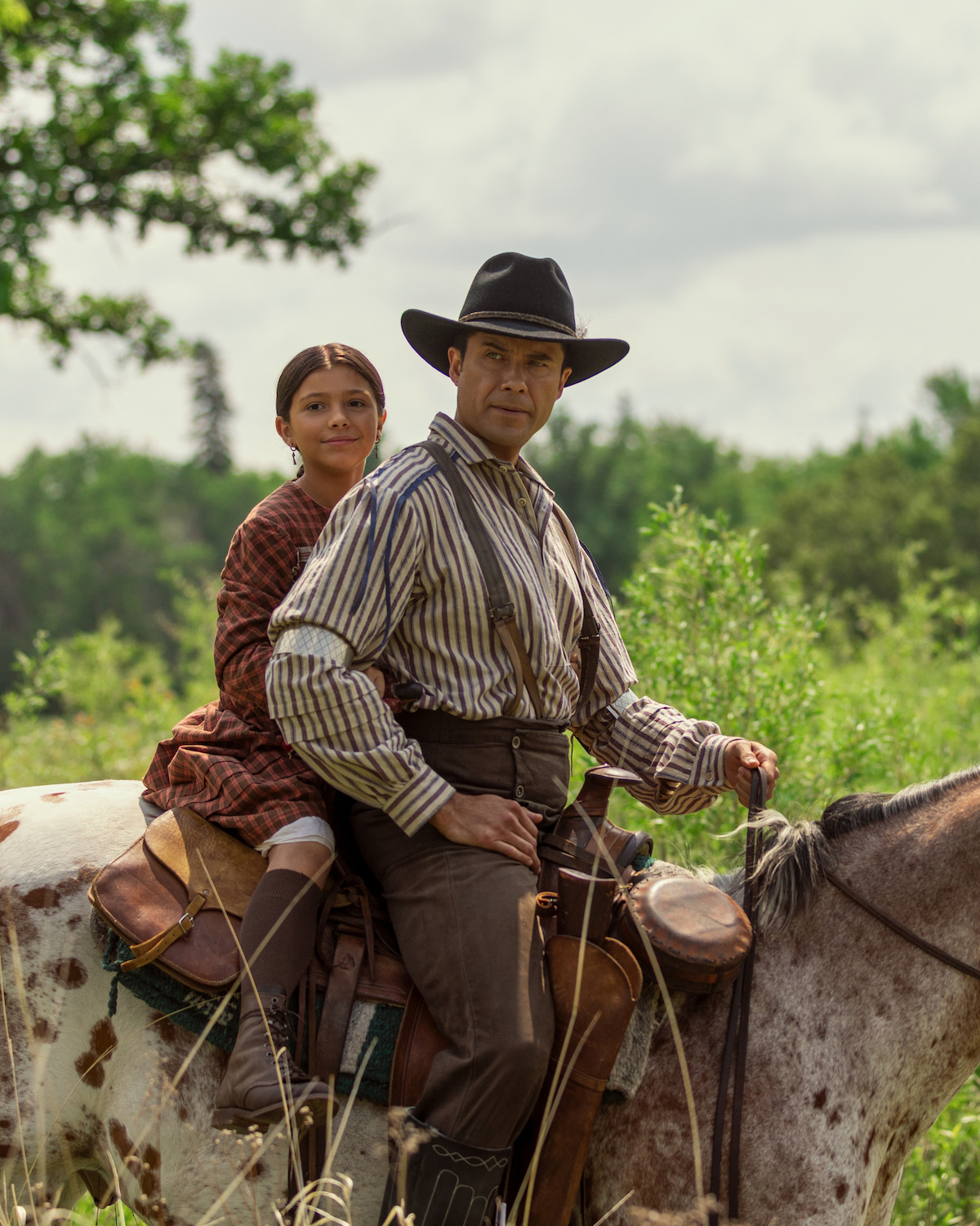 A man rides a horse with a little girl seated behind him.