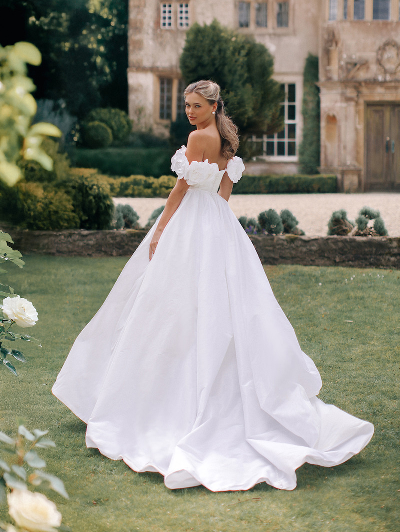 Woman in bridal dresses poses and looks off into the distance.