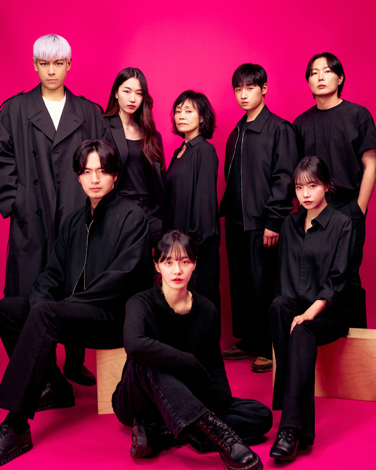 The cast of Season 2 of ‘Squid Game’ wears all black clothing while posing in front of a pink background.