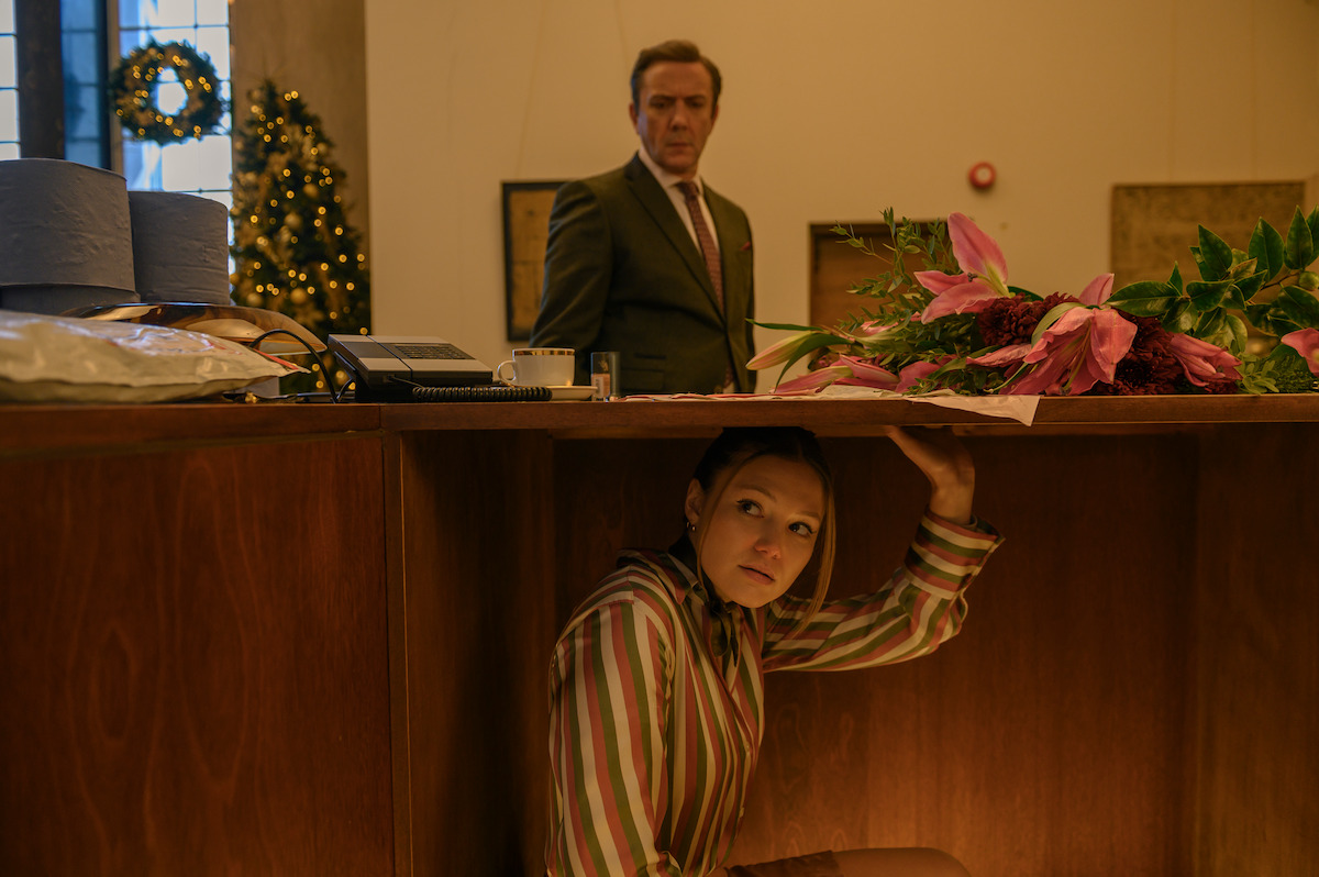 Olivia Holt as Sophia hides under a desk in ‘Jingle Bell Heist’