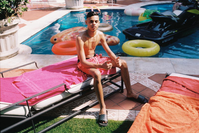 Um jovem posa para foto em frente a uma piscina