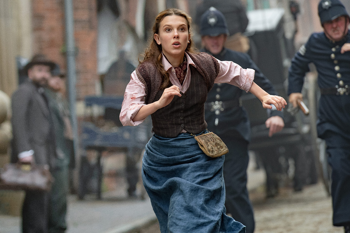  A teen girl in a Victorian dress runs from two policemen.