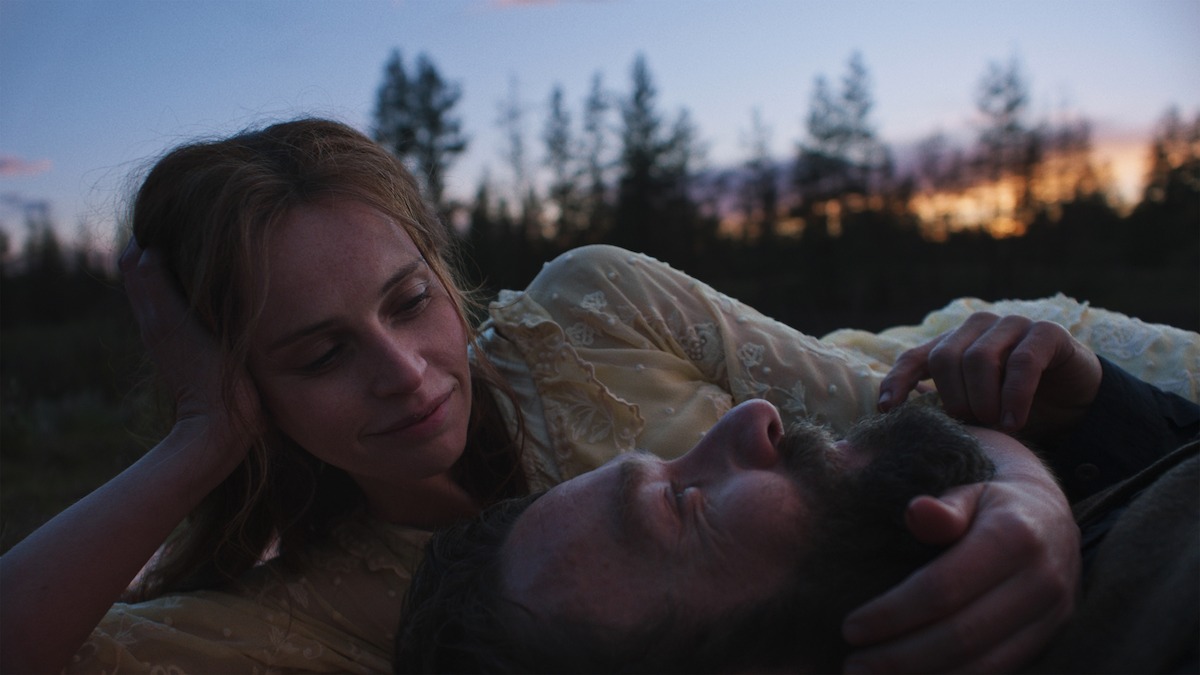 Felicity Jones as Gladys Oakley and Joel Edgerton as Robert Grainier laying on the ground.