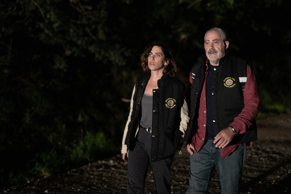 María León as Cruces and Carlos Blanco as Ríos stand on a trail in the dark in a still image from the series ‘The Asunta Case.’
