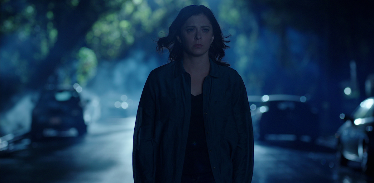 a woman walks by herself down a dark suburban street. 