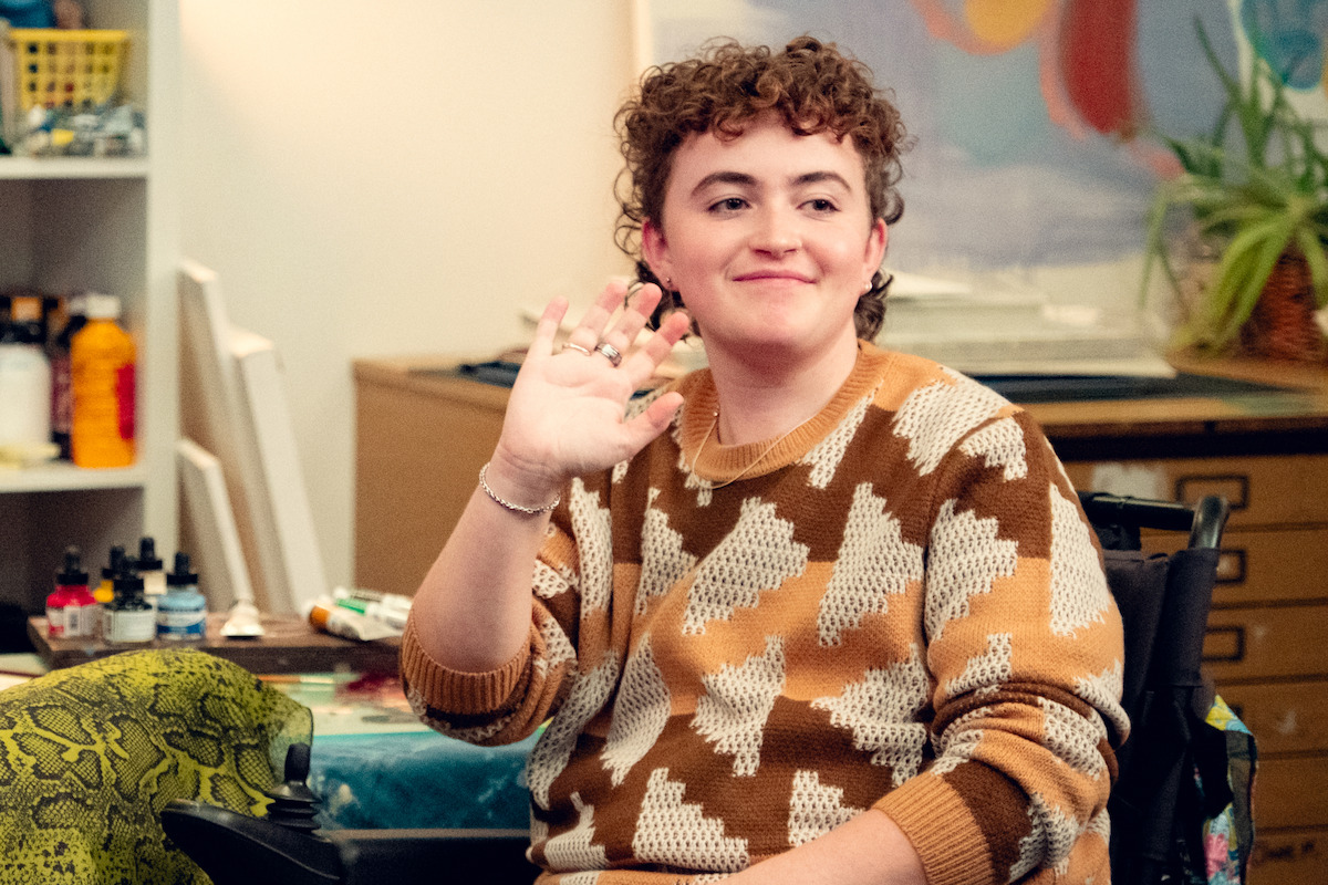 Ash Self as Felix waves and smiles in Season 3 of ‘Heartstopper.’