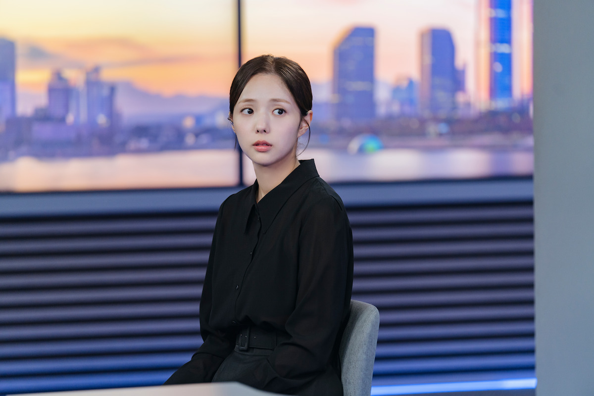 Chae Soo-bin sits in a news broadcast station wearing all black in an image from the series ‘When the Phone Rings.’