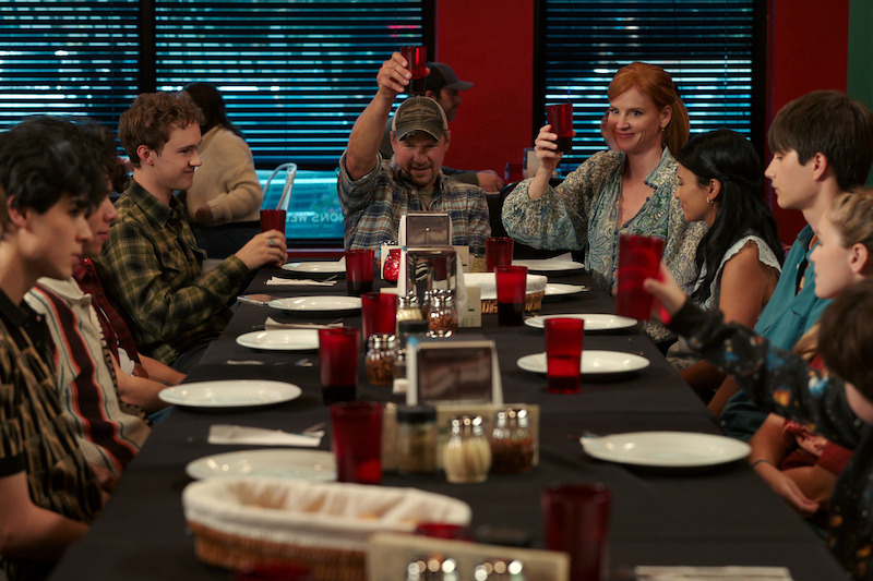 Blucas as George and Rafferty as Katherine holding up glasses at a table in ‘My Life with the Walter Boys’ Season 2
