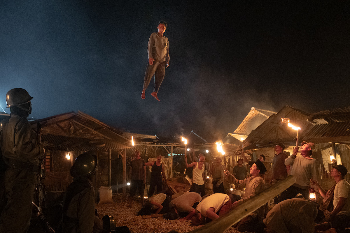Lukman Sardi as Wahyu floats in the sky above a village of people in an image from the anthology series ‘Joko Anwar’s Nightmares and Daydreams.’