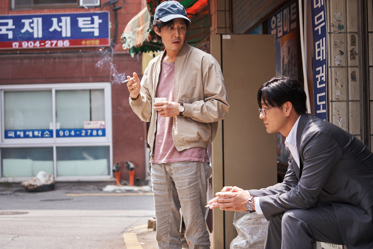 Lee Jung-jae as Seong Gi-hun and Park Hae-soo as Cho Sang-woo smoking outside in Seoul in ‘Squid Game’ Season 1.