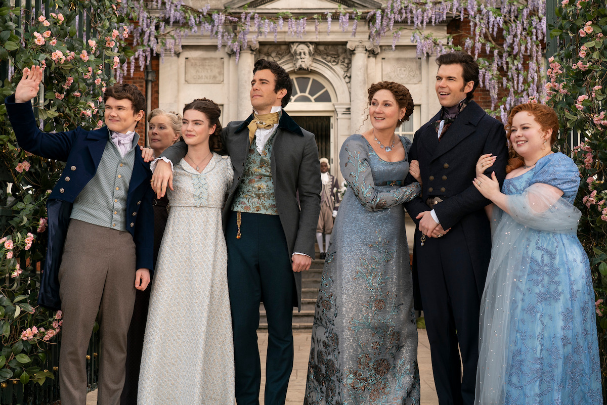 Will Tilston as Gregory Bridgerton, Florence Hunt as Hyacinth Bridgerton, Luke Thompson as Benedict Bridgerton, Ruth Gemmell as Lady Violet Bridgerton, Luke Newton as Colin Bridgerton and Nicola Coughlan as Penelope Featherington stand together in front of the ‘Bridgerton’ house in Season 3 of ‘Bridgerton’