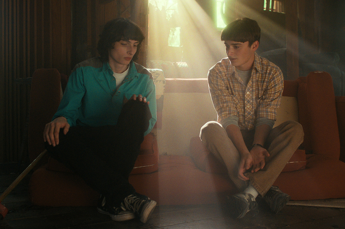  Two teenage boys sitting together in a light-filled living room space.