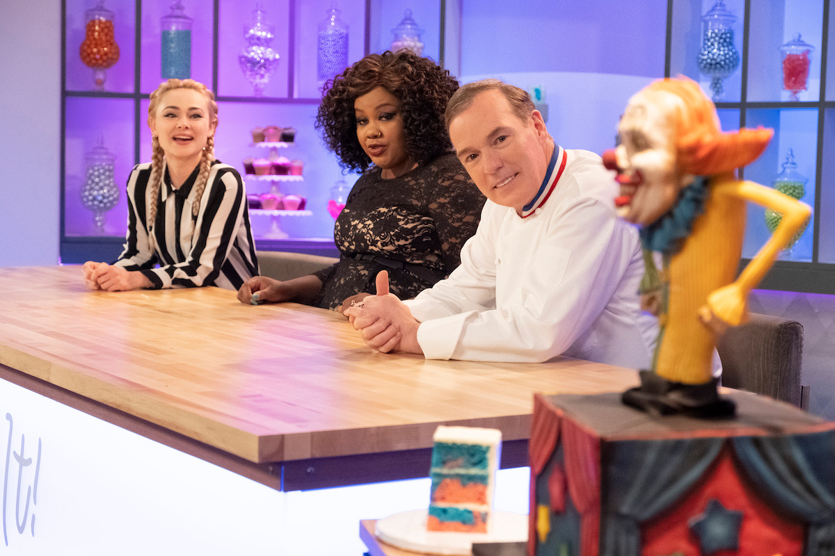 Judges observe a halloween themed cake thta looks like a scary clown. 