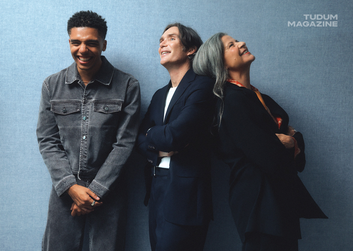 From left to right, Jay Lycurgo, Cillian Murphy, and Tracey Ullman caught in a moment of joy on set in front of a light blue wall.