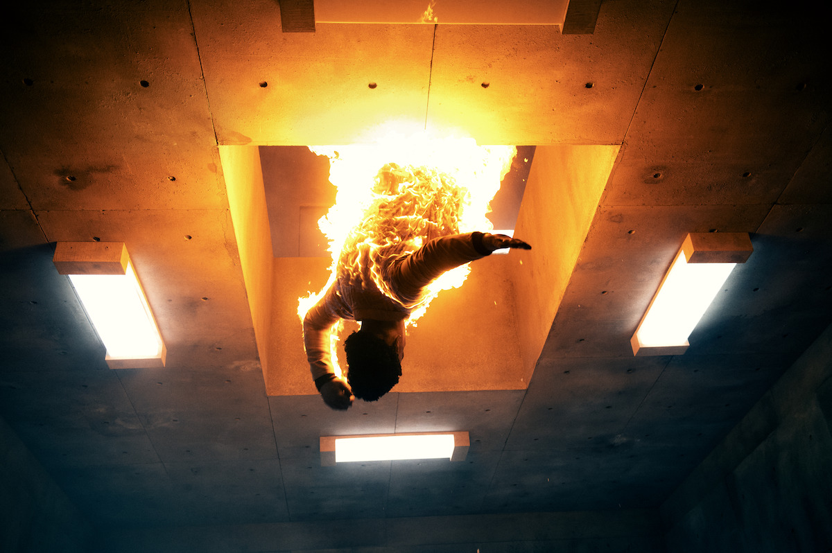 A burning body falls through a hole in a concrete floor in an image from the film ‘The Platform 2.’