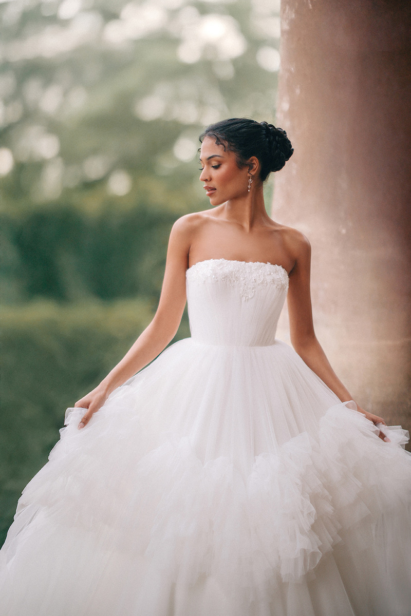 Woman in bridal dresses poses and looks off into the distance.
