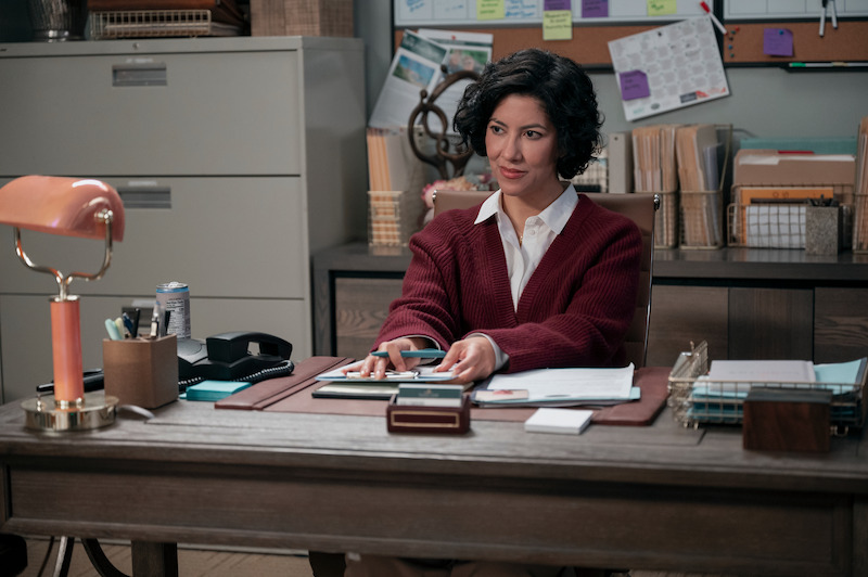Stephanie Beatriz as Didi sits at a desk in Season 1 of 'A Man on the Inside'