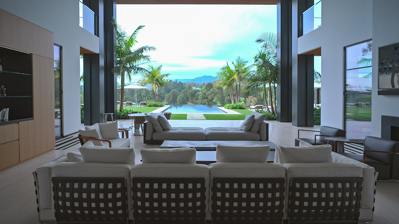  View of a luxurious living room looking out on a pool and grass veranda