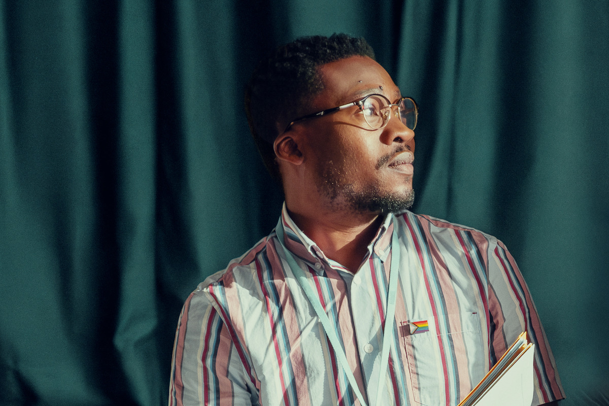 Fisayo Akinade as Mr. Ajayi sits at his desk in Season 1 of ‘Heartstopper.’