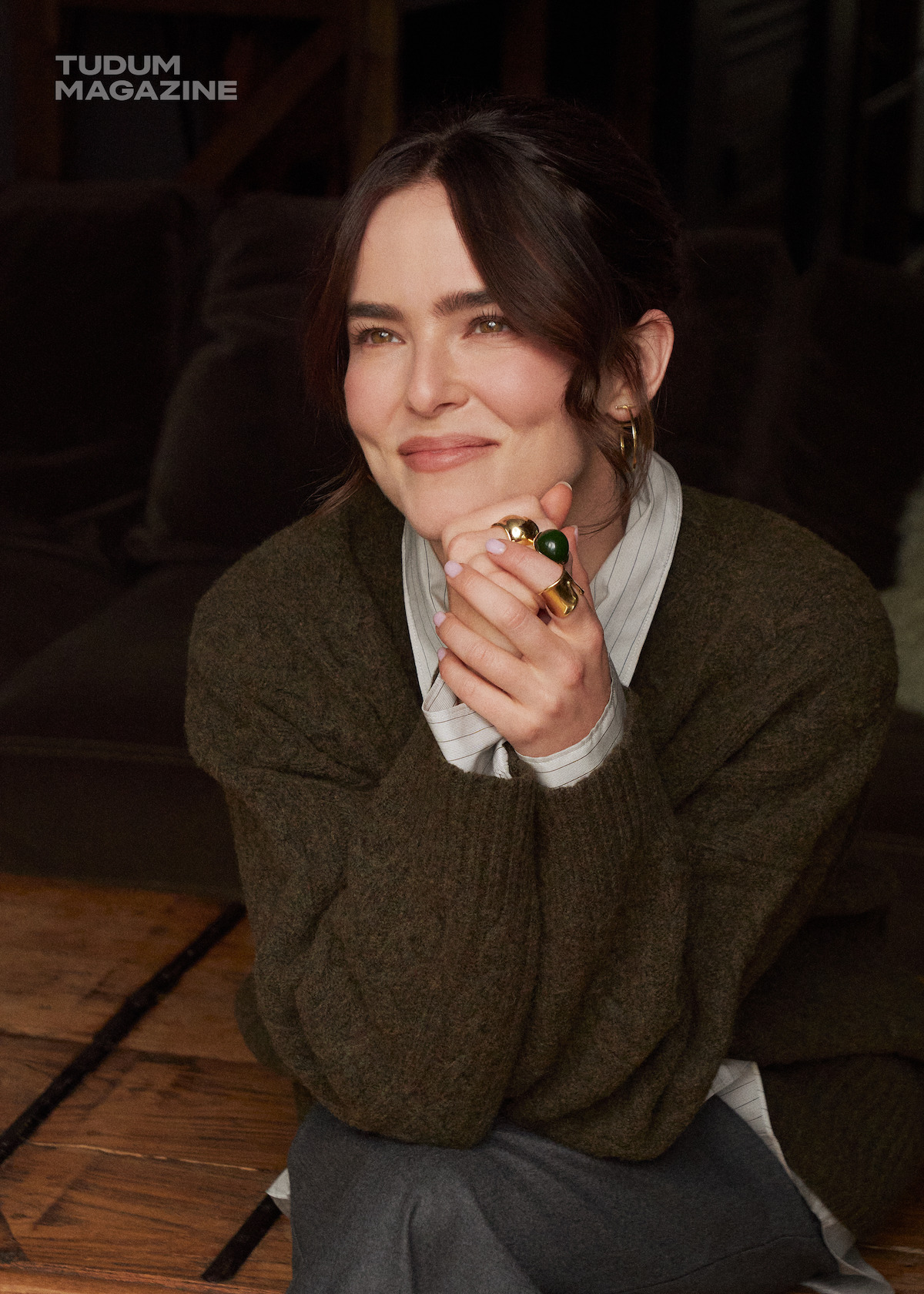 Actress Zoey Deutch in an dark olive green cable knit sweater.