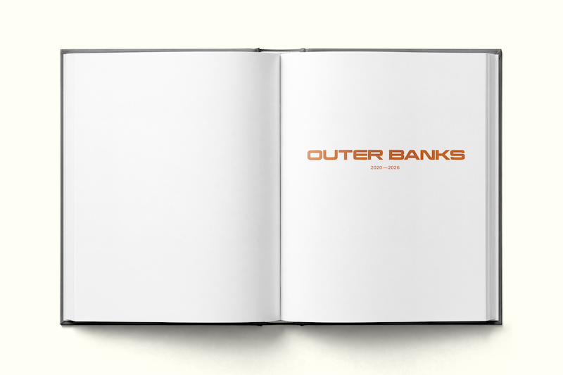 Open book on a light surface, showing blank white pages with the text "OUTER BANKS 2020–2023" centered on the right page, minimal design and clean environment.