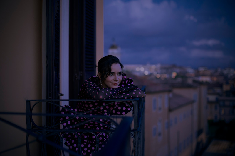 Lily Collins as Emily leans on a balcony railing in Season 4 of 'Emily in Paris'