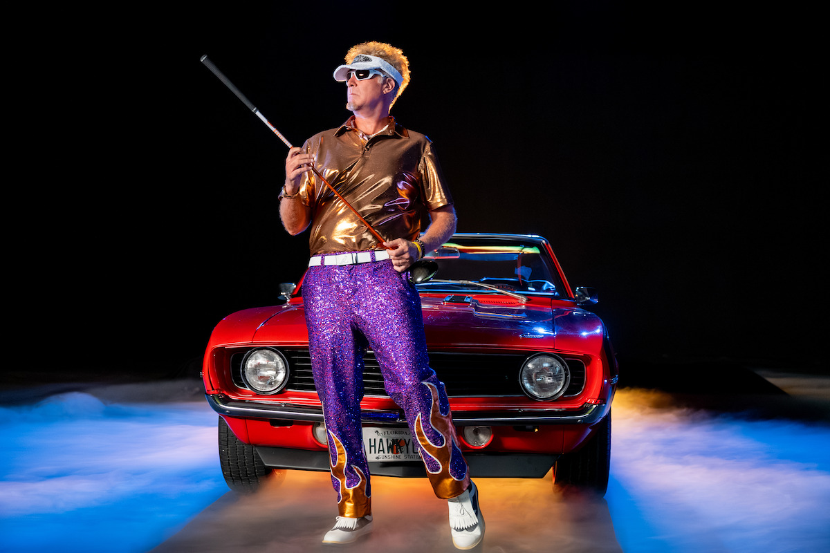 Man in shiny shirt, purple sequin pants, and white sunglasses holding a cane, standing in front of a red vintage convertible car with mist and colorful lighting, black background, dramatic and retro style scene.