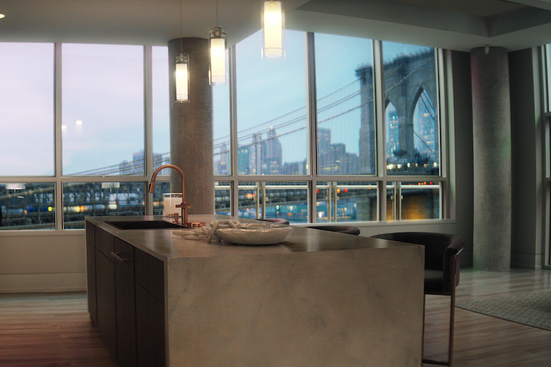 Marble kitchen island with floor to ceiling windows showing Brooklyn Bridge.