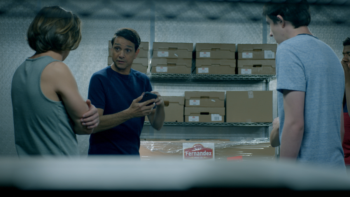 A picture of Daniel and two students in a warehouse with Fernandez meat boxes behind them. 