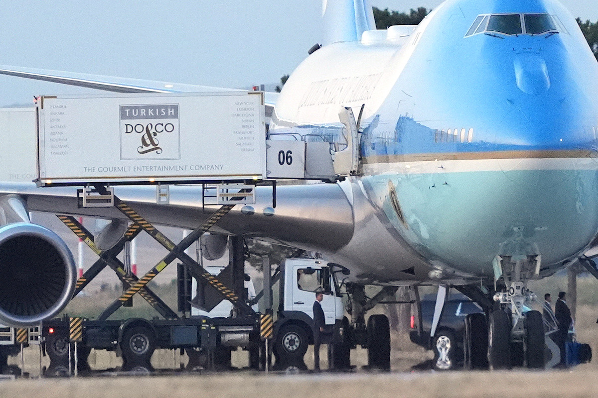 Large aircraft on runway with catering truck labeled Turkish Do&Co unloading supplies; crew members visible near front landing gear; daytime outdoor airport environment.