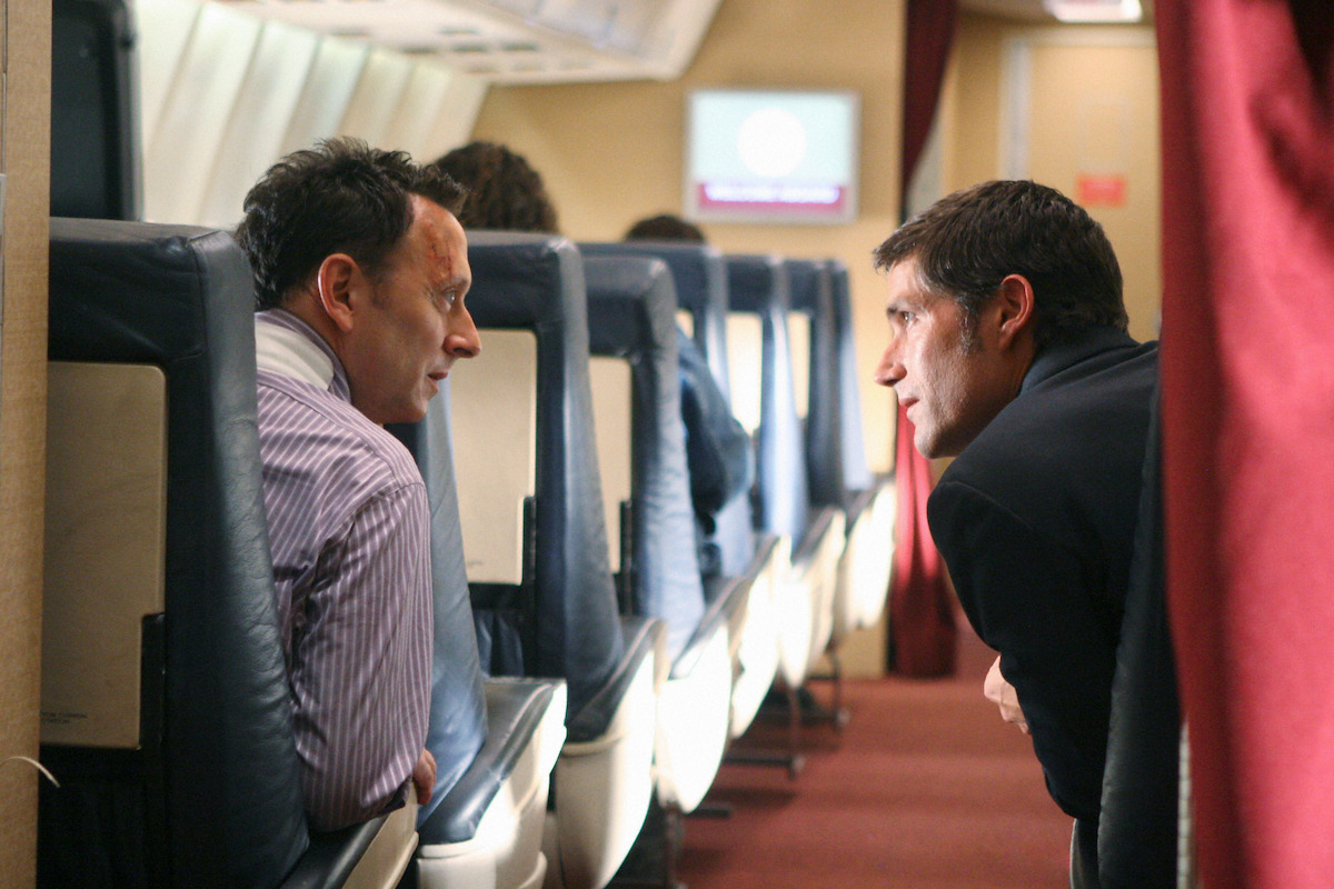 Michael Emerson and Matthew Fox speaking to each other on a plane.