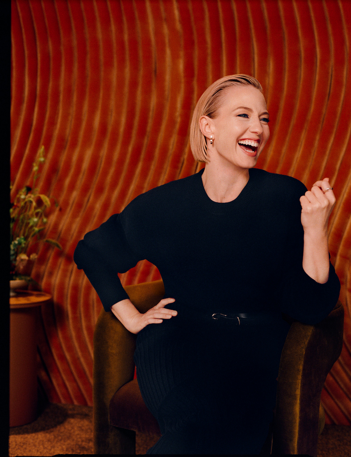 Carrie Coon wears a black ensemble and laughs at something offscreen.