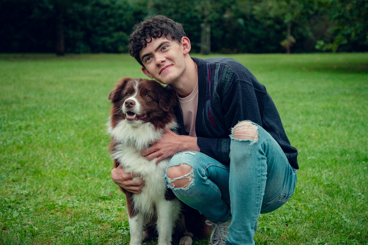 Joe Locke as Charlie cuddles with a dog in Season 3 of ‘Heartstopper.’