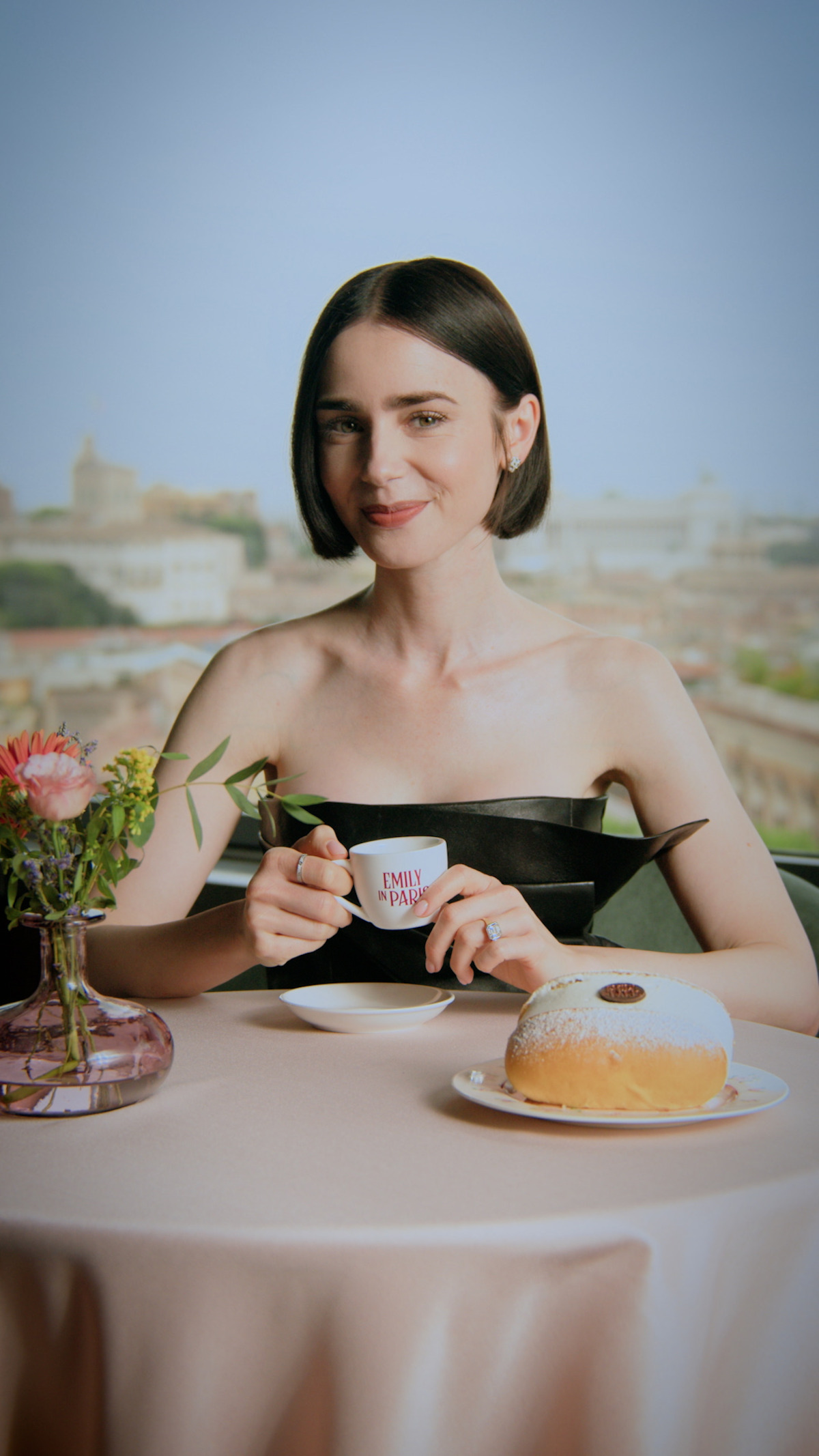 Lily Collins smiles holding a teacup 