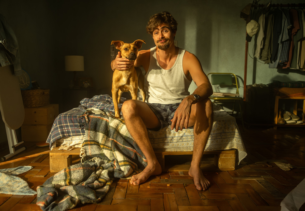 Pedro, interpretado por Rafa Vitti, e o cão Amendoim aparecem juntos, sentados em uma cama, em cena do filme ‘Caramelo’