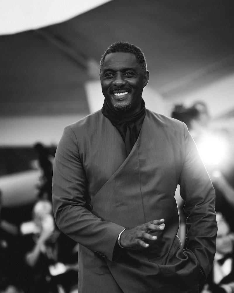 Idris Elba in a gray suit on the red carpet.