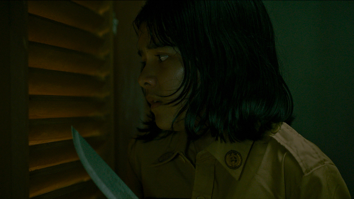 Anantya Kirana sebagai Alana memegang pisau di tirai kayu dalam gambar dari film 