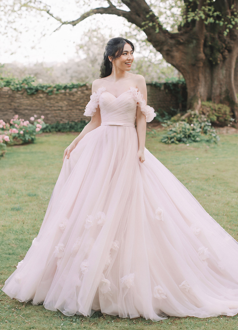 Woman in bridal dresses poses and looks off into the distance.