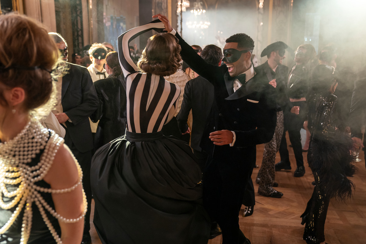 Lily Collins as Emily and Lucien Laviscount as Alfie dance together at a black-and-white ball in Season 4 of ‘Emily in Paris.’