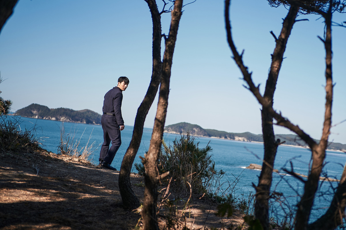 Wi Ha-jun as Hwang Jun-ho standing on a coastal cliff in ‘Squid Game’ Season 1.